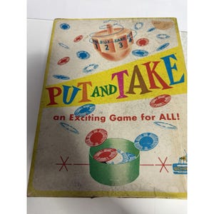 May include: A rectangular board game box titled PUT AND TAKE with a spinning top graphic, red and blue game chips, and the text an Exciting Game for ALL! The box features a yellow border, a green container illustration, and a small Schar logo.