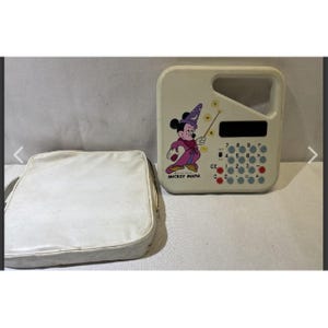 Puede incluir: Una calculadora vintage de Mickey Mouse "Mickey Math" con una carcasa y un asa blancas. La calculadora presenta un gráfico de Mickey Mouse con un atuendo de mago. También se incluye un estuche blanco.