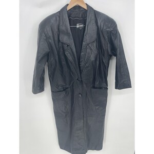 May include: Black leather coat with a notched collar, three-quarter sleeves, and two front pockets. The coat has a single-button closure and a tailored fit. The coat is hanging on a wooden hanger.
