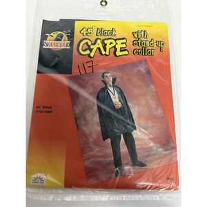 May include: A 45-inch black vinyl cape with a stand-up collar in its original plastic packaging. The packaging features the text 45 inch black CAPE with stand-up collar, Scarewear logo, and an illustration of a person wearing the black cape.