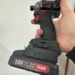 May include: A black and grey cordless impact driver with red detailing, held in a hand. The tool features the brand names "PARKSIDE" and "FLEX", and is labelled "18V 2.5 Ah Li-Ion".