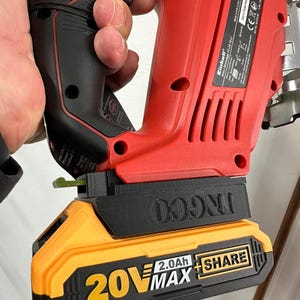 Könnte beinhalten: Eine rot-schwarze Akku-Stichsäge mit einem gelb-schwarzen 20V MAX Akku. Der Akku trägt die Aufschrift "2.0Ah + SHARE". Die Stichsäge wird von einer Hand gehalten.