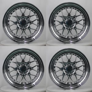 May include: A set of four circular chrome-finished automotive wheels featuring a multi-spoke mesh design. Each wheel has a polished metallic surface, a central hub cap, and a deep outer rim with visible bolt hardware around the inner circumference.