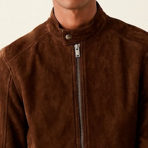 Könnte beinhalten: Eine braune Wildlederjacke mit Reißverschluss und Stehkragen.