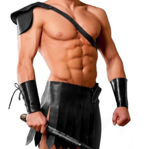 May include: A black leather kilt with a fringed hem and a matching leather shoulder strap. The kilt is worn with black leather wrist cuffs.