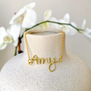 May include: A gold necklace with the name "Amy" spelled out in cursive.