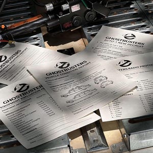 May include: A collection of black and white forms for the Ghostbusters, including a vehicle condition report, equipment evaluation report, and radio protocol. The forms feature the Ghostbusters logo and a drawing of the Ecto-1.