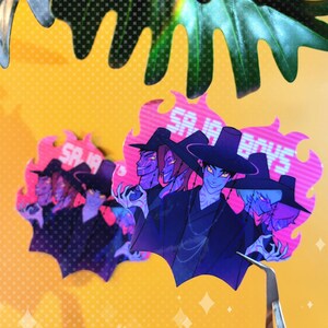 May include: Holographic stickers featuring a group of stylized characters with blue skin, wearing black hats and robes. The stickers have a pink and purple flame-like border with the text "SA IA BOYS". The background is yellow.