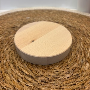 Könnte beinhalten: Ein runder Holzständer mit natürlicher Holzoptik. Der Ständer ist aus hellem Holz gefertigt und hat eine glatte Oberfläche.