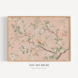 Puede incluir: Una impresión enmarcada con una ilustración en acuarela de pájaros posados en ramas florecidas. La obra de arte tiene una paleta de colores suaves y pastel con un fondo rosa claro y un marco de madera. El texto "NINI ART BRUSH" está en la parte inferior.
