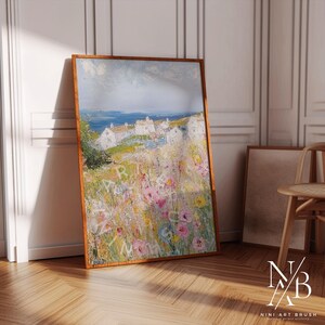 Op de afbeelding: Een schilderij van een kustsc&egrave;ne met witte huizen en een veld vol kleurrijke bloemen. De lucht is blauw met witte wolken. Het schilderij is ingelijst in een houten lijst.