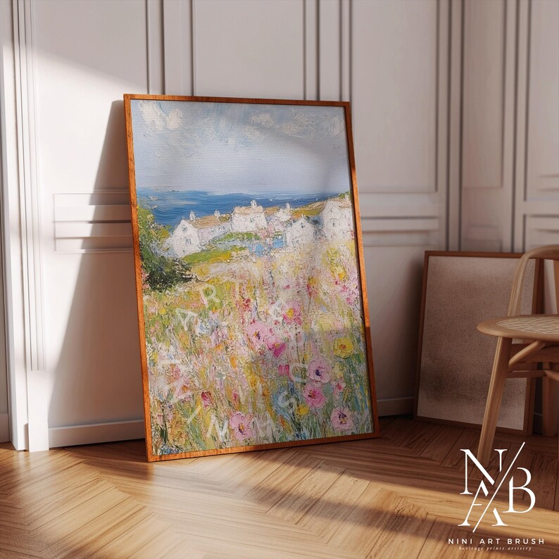 Op de afbeelding: Een schilderij van een kustsc&egrave;ne met witte huizen en een veld vol kleurrijke bloemen. De lucht is blauw met witte wolken. Het schilderij is ingelijst in een houten lijst.