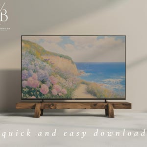 Op de afbeelding: Een grote flatscreen-tv met een kustlandschapschilderij met een pad, bloemen en de oceaan. De tv staat op een rustieke houten standaard. De woorden "quick and easy download" staan onderaan.
