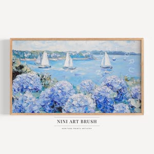 May include: A painting of a seascape with sailboats in the distance and a field of blue hydrangeas in the foreground. The painting is framed in a light wood frame.