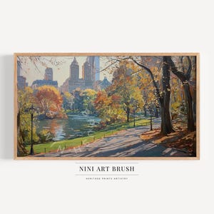 May include: A framed landscape painting of a park scene in autumn. The artwork depicts a lake, trees with fall foliage, a pathway, and city buildings in the background. The text "NINI ART BRUSH" is at the bottom.