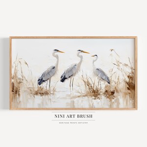 May include: A painting of three gray herons standing in a marsh with tall reeds. The herons are painted in a realistic style with soft brushstrokes. The background is a light blue and white, creating a serene and peaceful atmosphere.