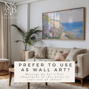 Op de afbeelding: Een ingelijste landschapsafdruk hangt boven een beige bank met kussens. De afdruk toont een kustlandschap met een pad, bloemen en de zee. Tekst op de afbeelding luidt "PREFER TO USE AS WALL ART?" en "NINI ART BRUSH".