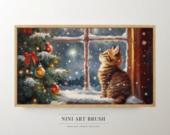 May include: A framed print depicts a cozy winter scene. A tabby kitten sits on a snowy windowsill, gazing upward at falling snow. A decorated Christmas tree with red bows and ornaments is to the left. The text "NINI ART BRUSH" and "HERITAGE PRINTS ARTISTRY" are at the bottom.