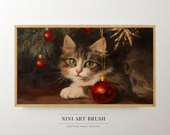 May include: A tabby cat with green eyes sits under a Christmas tree with red ornaments. The cat is looking at the camera. The cat is resting its paw on a red ornament.