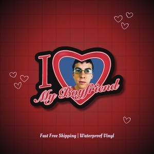 May include: A sticker with a red heart-shaped design that says "I My Boyfriend." The heart contains a photo of a man wearing glasses. The background is red with white heart outlines.