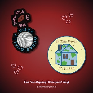 May include: Two vinyl stickers. One is black and shaped like a disco ball with the text KISS ALL THE TIME. DISCO, OCCASIONALLY. The other is a round, cream-colored sticker featuring a blue and green house with the text In This World It's Just Us.