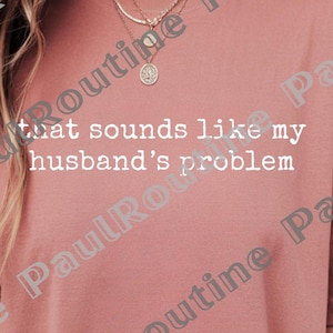 May include: Dusty rose t-shirt with the text "that sounds like my husband's problem" in white. The shirt is a solid color and has short sleeves. The image also includes SVG and PNG file icons.