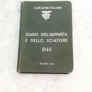Puede incluir: Un libro verde vintage titulado "DIARIO DELL'ALPINISTA E DELLO SCIATORE 1949" de Tavecchi. La portada presenta el texto "CLUB ALPINO ITALIANO" y un escudo. El libro es rectangular y parece estar en buen estado.