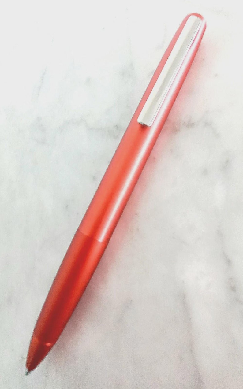 May include: A vibrant red pen with a silver clip. The pen has a sleek, streamlined design and a glossy finish. The pen is a writing instrument.