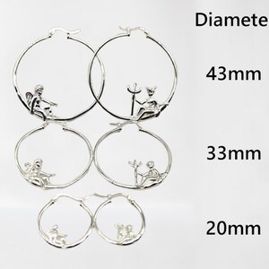 May include: Three pairs of silver hoop earrings with different sized diameters: 43 mm, 33 mm, and 20 mm. Each hoop features a small, detailed design of a cherub.