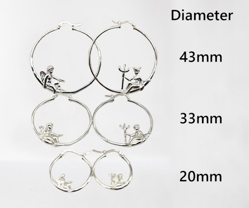 May include: Three pairs of silver hoop earrings with different sized diameters: 43 mm, 33 mm, and 20 mm. Each hoop features a small, detailed design of a cherub.