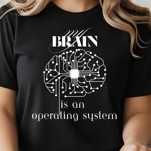 May include: Black t-shirt with the text "My Brain is an operating system" in white. The design features a stylized brain graphic with circuit board elements, creating a tech-inspired look. The shirt is a classic crew neck.