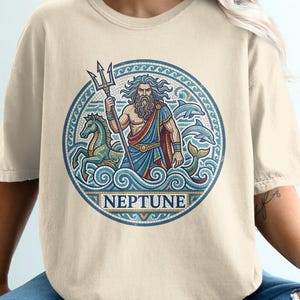 Neptune graphic on tan t-shirt with trident, sea creatures, and waves.