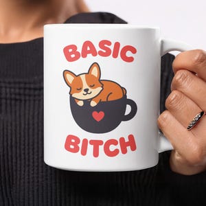 Könnte beinhalten: Weiße Keramik-Tasse mit den roten Worten "BASIC BITCH" und einem Cartoon-Corgi-Hund in einer schwarzen Teetasse mit rotem Herz. Die Tasse hat einen weißen Henkel.