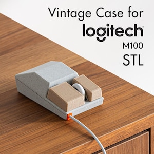 Peut inclure: Un boîtier gris imprimé en 3D pour une souris Logitech M100. Le boîtier possède deux boutons et une molette de défilement. Le boîtier est posé sur une surface en bois. Vintage Case for logitech M100 STL