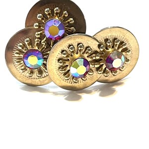 Può includere: Un paio di orecchini dorati con strass rossi iridescenti incastonati in un design circolare.