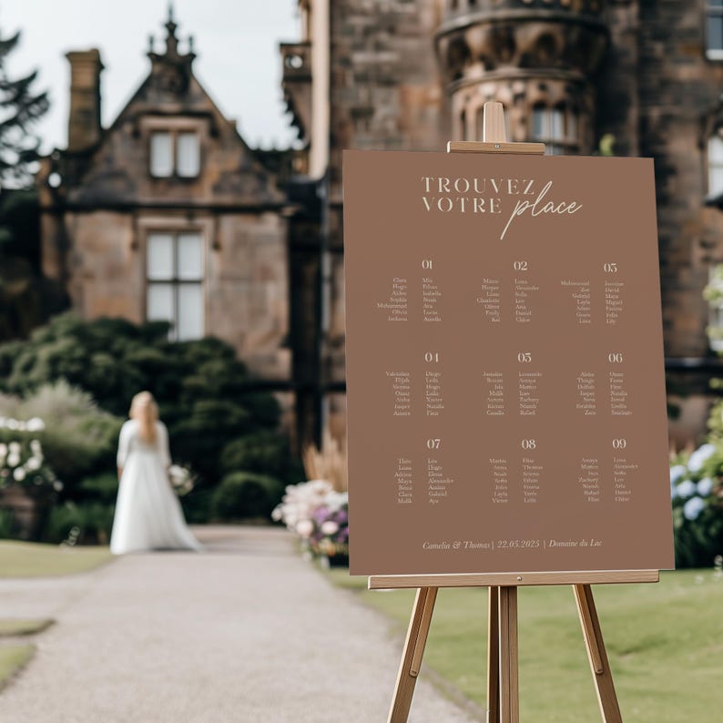 May include: A brown seating chart with the text "TROUVEZ VOTRE place" in a light brown font. The chart is divided into nine sections, each with a table number and a list of names. The chart is on a wooden easel.