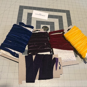 May include: A selection of velvet ribbon spools in shades of navy, burgundy, purple, and yellow. The ribbon is wound on cardboard spools, suitable for crafts. A small card with the text "LIVELOGY" is visible, along with a thank you sticker.
