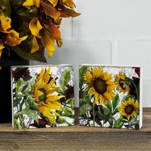May include: A white ceramic mug with a black handle and the text "But First, Coffee" in a bold, black font. The mug is sitting on a wooden surface. The mug is approximately 4 inches tall.