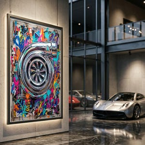 May include: A framed wall art piece featuring a metallic silver turbocharger illustration centred against a vibrant, multi-coloured graffiti background with splatters of blue, pink, yellow, and orange paint, displayed on a concrete pillar.