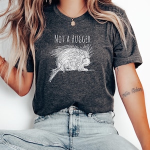May include: A dark grey t-shirt with a white graphic of a porcupine and the text "Not a hugger".