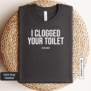 a black t - shirt that says, i clogged your toilet in no