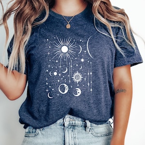May include: A navy blue t-shirt with a white celestial design featuring a sun, moon, and stars. The shirt is made of a soft, comfortable material.