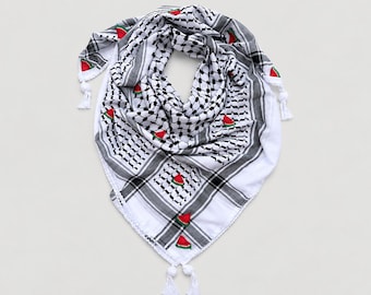 May include: A square scarf featuring a traditional black and white checkered keffiyeh pattern with embroidered red, green, and black watermelon slice motifs. The scarf has white fabric borders and is finished with white tassels at the corners.