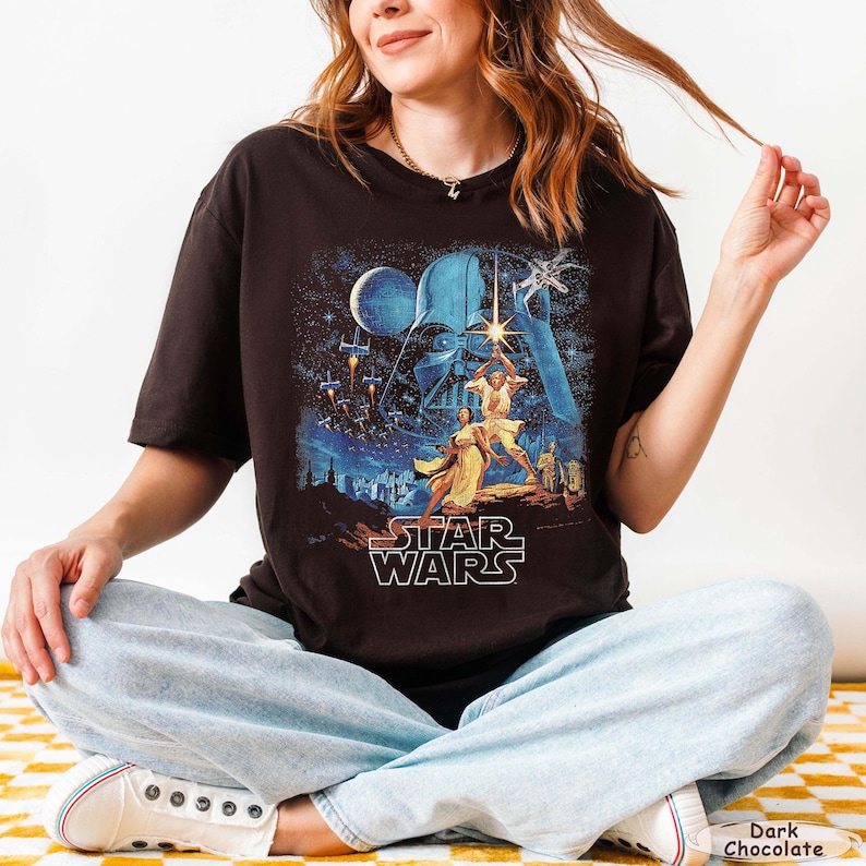 Pu&ograve; includere: T-shirt color cioccolato fondente con grafica di Star Wars. Il design mostra Darth Vader, Luke Skywalker e altri personaggi. Il logo di Star Wars &egrave; bianco.