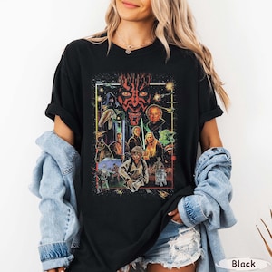 May include: Black t-shirt featuring a Star Wars graphic with various characters and scenes. The design includes Darth Maul, Yoda, and Luke Skywalker, among others, in a rectangular frame. The word "Black" is printed at the bottom right.