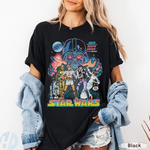 May include: Black Star Wars graphic tee featuring Darth Vader and other characters. The design includes the text "STAR WARS" in a colorful, retro font, and the phrase "THE BATTLE WITH DARTH VADER TO THE DEATH!"