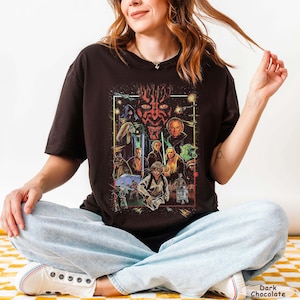 May include: Dark chocolate-colored t-shirt featuring a Star Wars graphic. The graphic includes various characters and scenes from the Star Wars saga, with a prominent image of Darth Maul. The shirt is a crew neck style.
