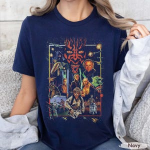 May include: Navy blue t-shirt featuring a colorful graphic of Star Wars characters, including Darth Maul, Yoda, and Luke Skywalker. The design is framed with a white border and includes the word "Navy" at the bottom.