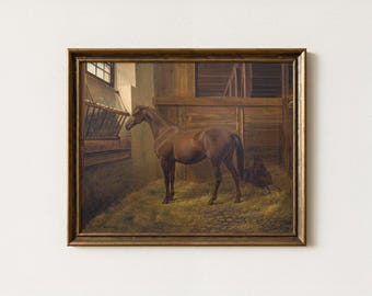 May include: A framed oil painting depicting a brown horse standing inside a wooden stable. The horse is positioned on a bed of straw near a hay rack. The scene includes wooden wall panels and a small window, all enclosed in a dark gold frame.