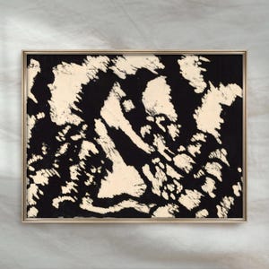 May include: A rectangular wall art piece in a thin gold frame featuring an abstract design with high-contrast black and cream-coloured shapes. The composition displays irregular, jagged patches of cream against a solid black background.